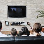 family wathching flat tv at modern home indoor